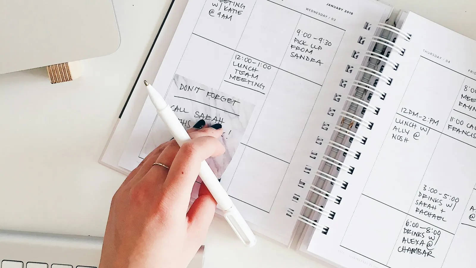 En hand som skriver datum i en spiralbunden kalender