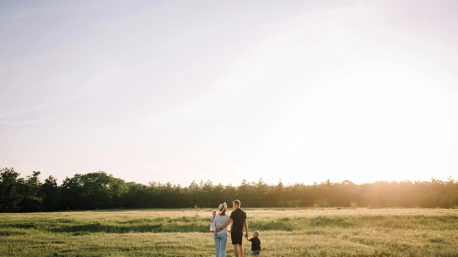 En familj som går tillsammans över ett solbelyst fält